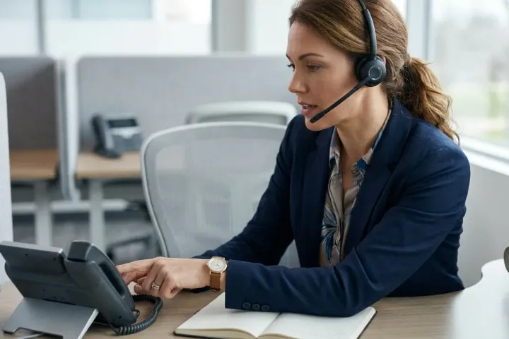 Une consultante à son bureau, en appel client avec un casque